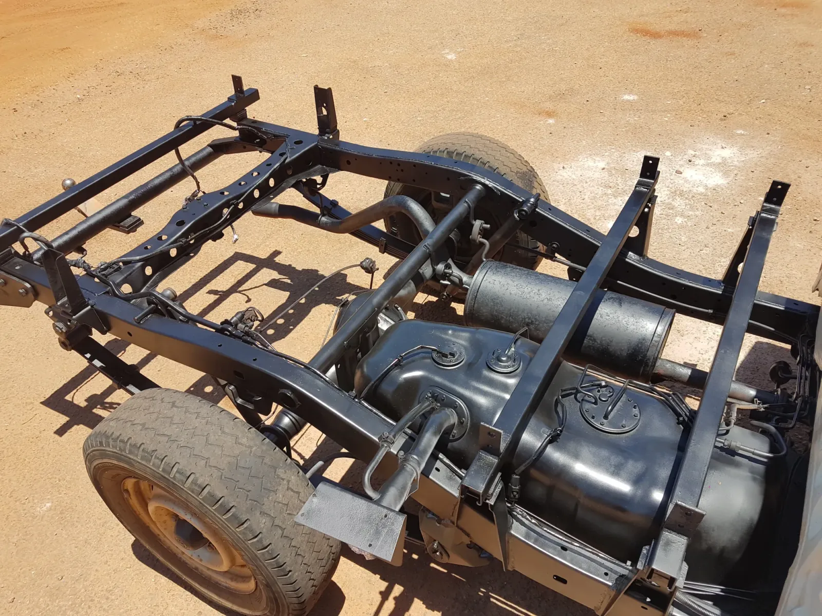 Top-down view of fully sealed ladder-frame chassis showing rust-proofed dual fuel tanks, exhaust system, and chassis rails by Kimberley Auto Care