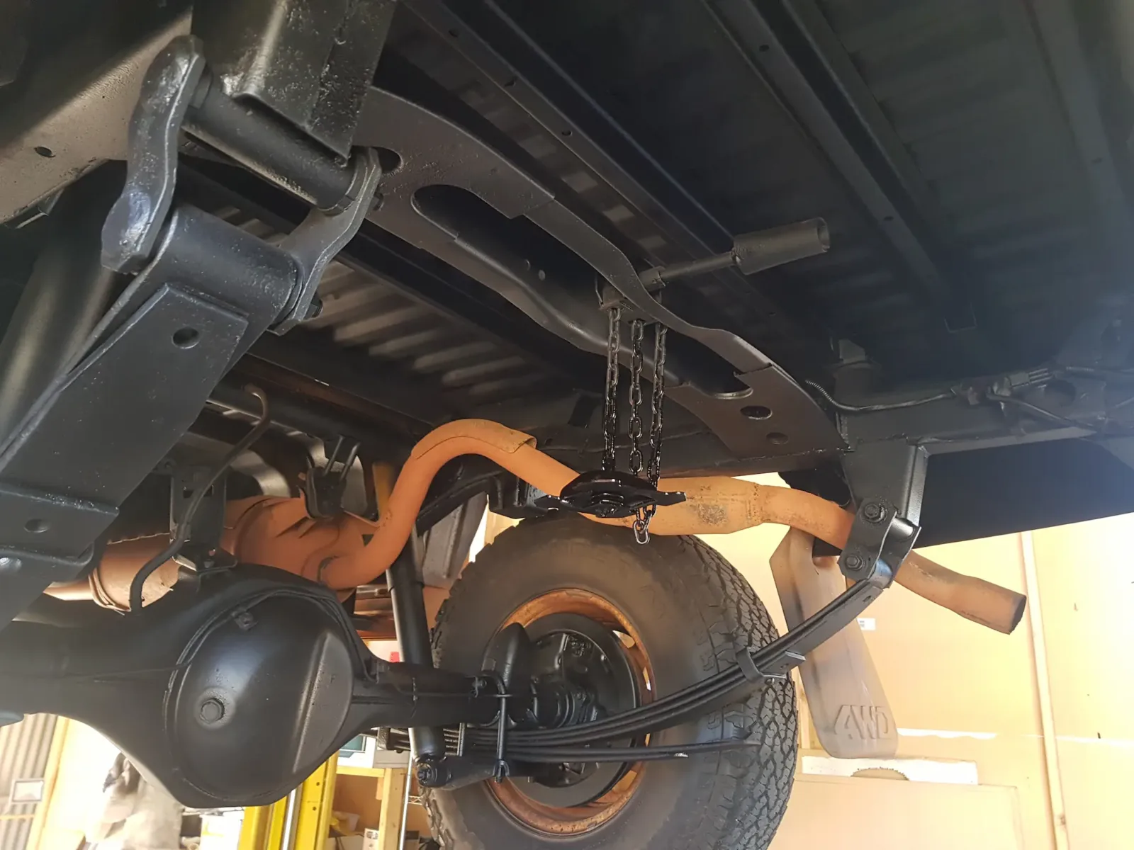 Undercarriage rear view showing rust-proofed chassis rails, sealed differential housing, leaf springs, and spare tyre chain carrier after treatment by Kimberley Auto Care