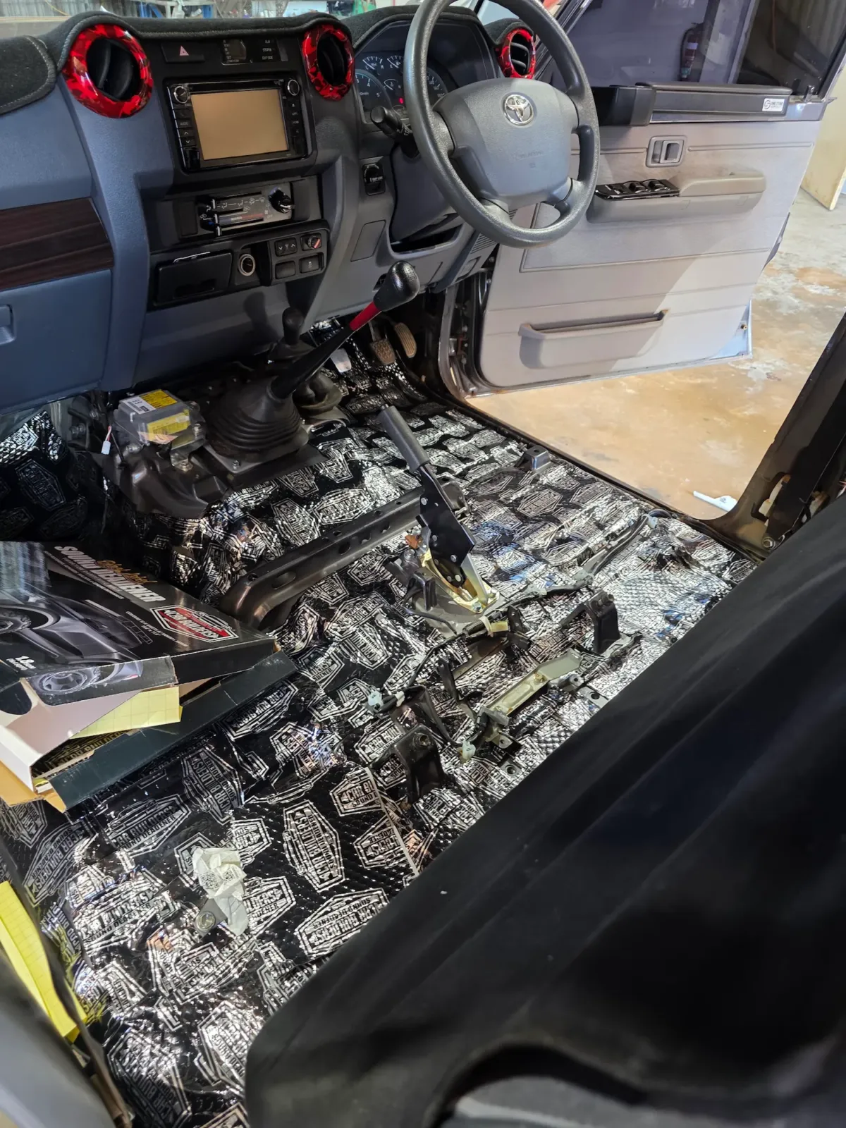 Sound deadening material being installed on vehicle cabin floor by Kimberley Auto Care