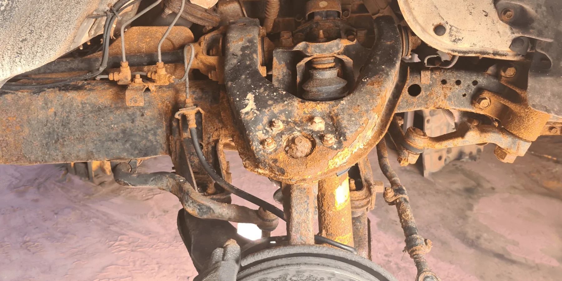 Before rustproofing showing heavy rust and corrosion on underbody chassis control arms and suspension components in Broome