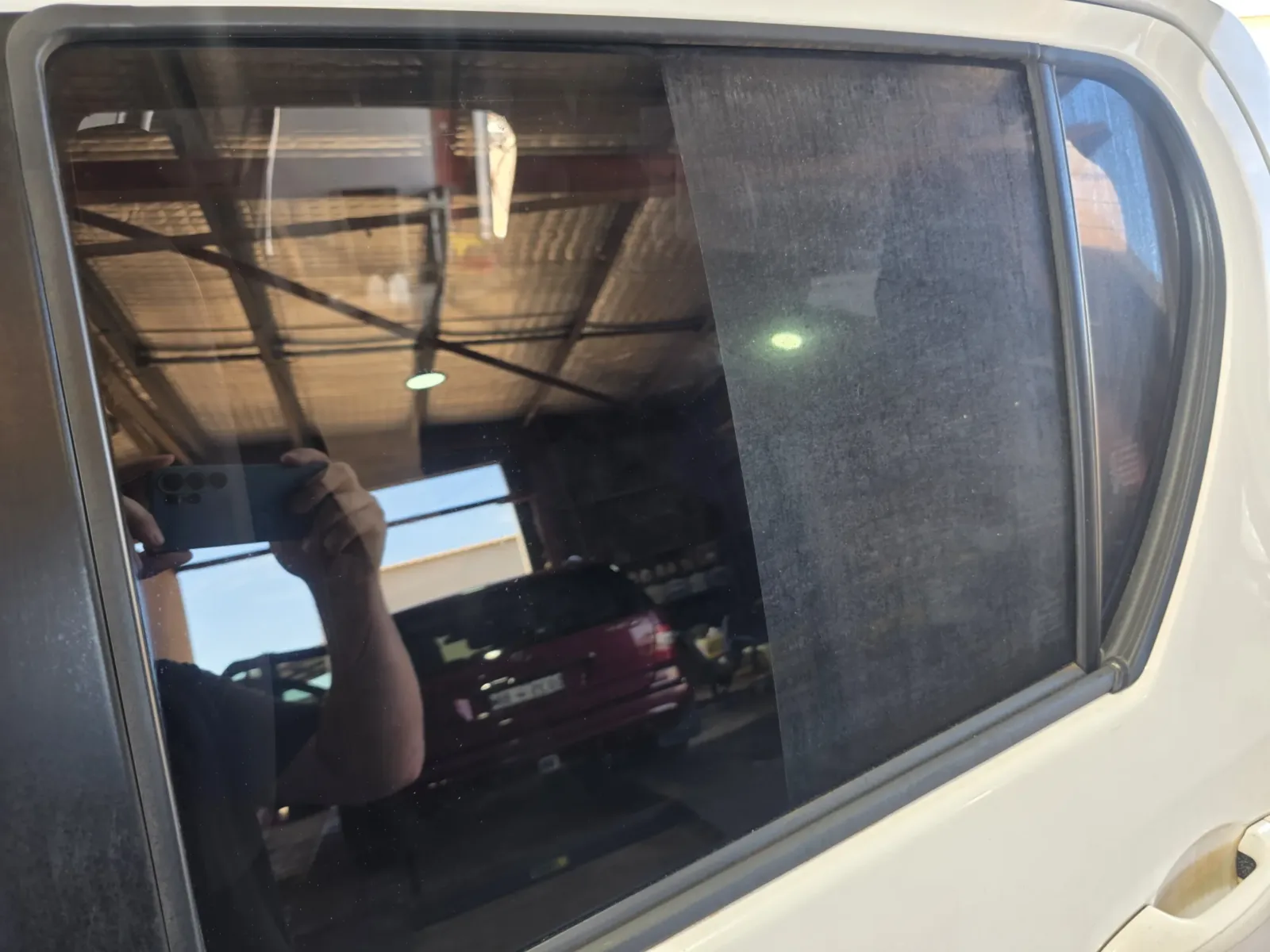 Before and after window tinting on rear passenger window showing old faded tint replaced with new dark tint by Kimberley Auto Care
